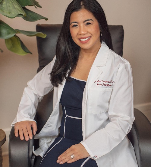 Eliza Mae Tangonan, APN-C, PMHNP-BC, seated in a white clinical coat over a navy dress.